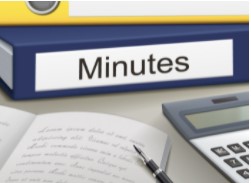 A binder labeled "Minutes" sits on a desk next to an open notebook with handwritten notes, a pen, and a calculator, ready to guide you through the meeting with Roberts-Rules-help.