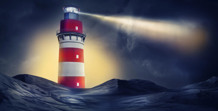 A red and white striped lighthouse emits a bright beam of light through a dark, cloudy sky, illuminating the surrounding area.